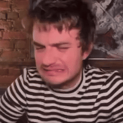 A Man In A Striped Shirt Is Crying And Making A Funny Face . GIF