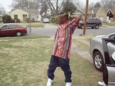 A Man In A Striped Shirt Is Dancing In Front Of A Car GIF