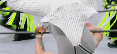 A Man In A Striped Shirt Is Doing A Handstand In A Boxing Ring . GIF