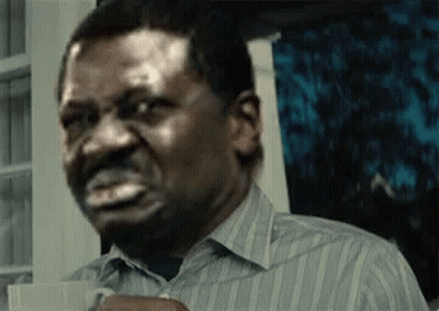 A Man In A Striped Shirt Is Holding A Cup Of Coffee And Making A Face . GIF
