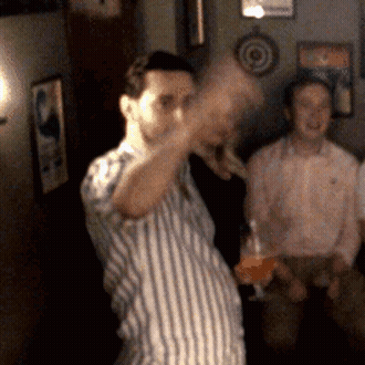 A Man In A Striped Shirt Is Holding A Glass GIF
