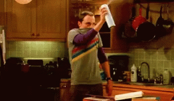 A Man In A Striped Shirt Is Holding A Napkin In A Kitchen GIF