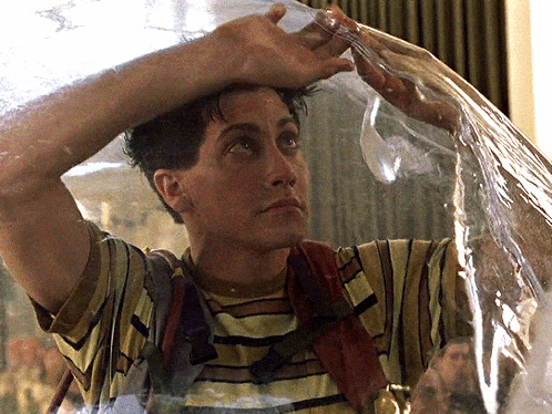 A Man In A Striped Shirt Is Holding A Plastic Bag Over His Head And Water Is Coming Out Of It GIF