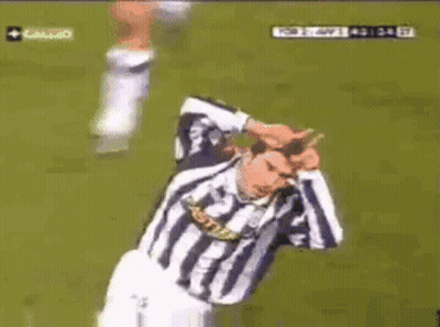 A Man In A Striped Shirt Is Kneeling Down On A Field GIF