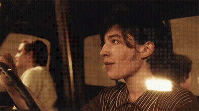A Man In A Striped Shirt Is Looking At Something In A Mirror GIF