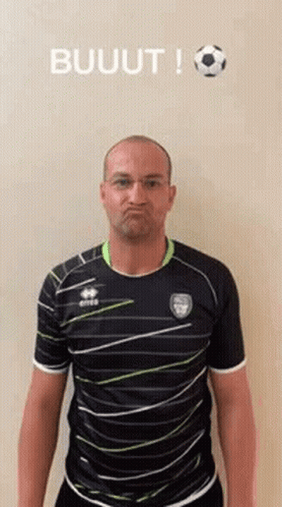 A Man In A Striped Shirt Is Making A Funny Face While Standing In Front Of A Soccer Ball . GIF