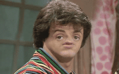 A Man In A Striped Shirt Is Making A Funny Face With His Mouth Open . GIF