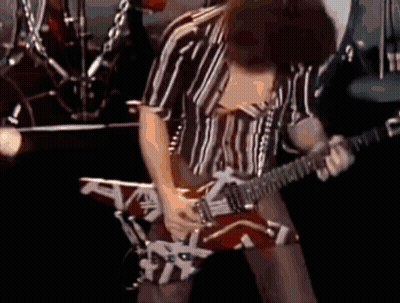 A Man In A Striped Shirt Is Playing A Guitar On Stage GIF