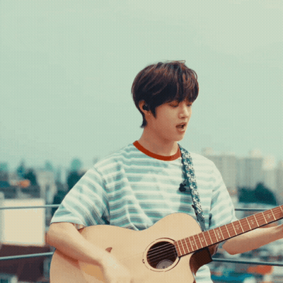 A Man In A Striped Shirt Is Playing A Guitar GIF