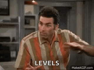 A Man In A Striped Shirt Is Sitting At A Table With His Hands Up And Says `` Levels '' . GIF