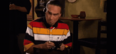 A Man In A Striped Shirt Is Sitting At A Table With The Words I 'M On It Above Him . GIF
