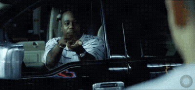 A Man In A Striped Shirt Is Sitting In A Car And Looking Out The Window GIF
