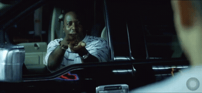 A Man In A Striped Shirt Is Sitting In A Car And Pointing At Something GIF