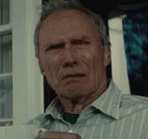 A Man In A Striped Shirt Is Sitting In Front Of A Window Holding A Cup . GIF