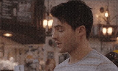 A Man In A Striped Shirt Is Standing In Front Of A Bar . GIF