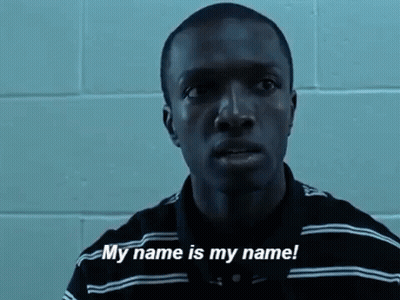 A Man In A Striped Shirt Is Standing In Front Of A Brick Wall And Says `` My Name Is My Name '' . GIF