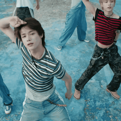 A Man In A Striped Shirt Is Standing In Front Of A Group Of People GIF