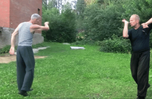 A Man In A Striped Shirt Is Standing In The Grass GIF