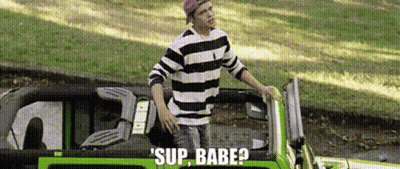 A Man In A Striped Shirt Is Standing Next To A Green Car With The Words Sup Babe Written On It . GIF