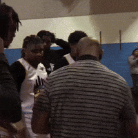 A Man In A Striped Shirt Stands In A Crowd Of People GIF