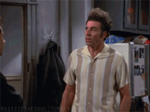 A Man In A Striped Shirt Stands In Front Of A Fridge GIF