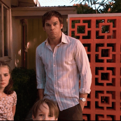 A Man In A Striped Shirt Stands In Front Of An Orange Block GIF