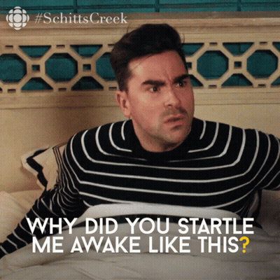 A Man In A Striped Sweater Is Laying On A Bed With The Words " Why Did You Startle Me Awake Like This " GIF