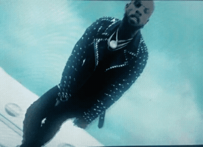 A Man In A Studded Jacket And Sunglasses Is Standing On A Plane GIF