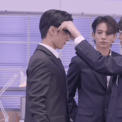 A Man In A Suit Adjusts His Glasses While Another Man Looks On GIF