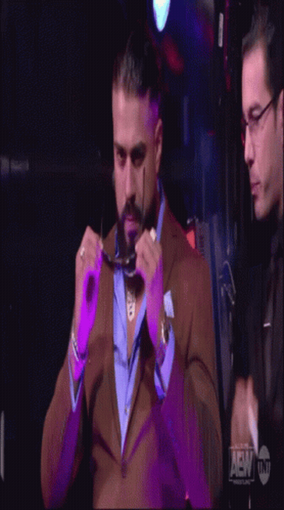 A Man In A Suit Adjusts His Glasses While Another Man Looks On GIF