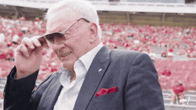 A Man In A Suit Adjusts His Sunglasses In Front Of A Crowd In A Stadium GIF