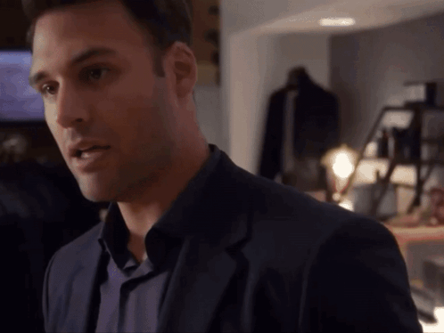 A Man In A Suit And A Blue Shirt Is Looking At The Camera GIF