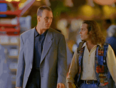 A Man In A Suit And A Man In A Colorful Vest Are Walking Down The Street GIF