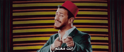 A Man In A Suit And A Red Hat Is Pointing At The Camera GIF