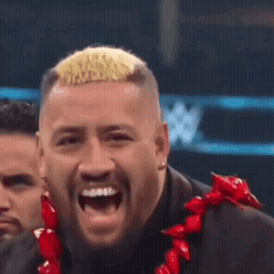 A Man In A Suit And A Red Lei Is Laughing . GIF