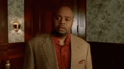 a man in a suit and a red shirt is standing in a room .