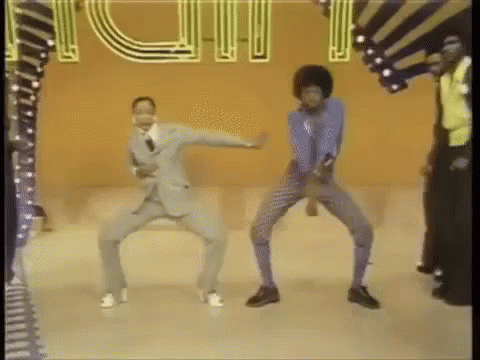 A Man In A Suit And A Woman In A Blue Shirt Are Dancing On A Stage . GIF