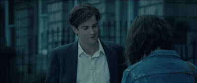 A Man In A Suit And A Woman In A Denim Jacket Are Talking To Each Other GIF