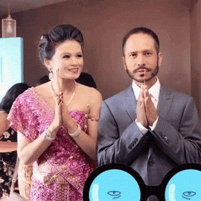 A Man In A Suit And A Woman In A Pink Dress Praying GIF