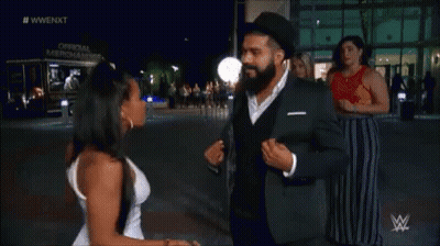 A Man In A Suit And A Woman In A White Dress Are Dancing Together . GIF