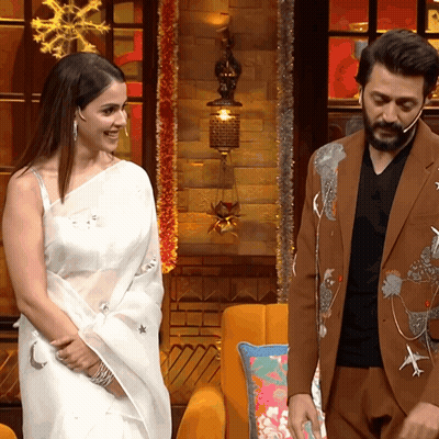 A Man In A Suit And A Woman In A White Saree Are Standing Next To Each Other GIF