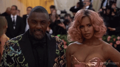 A Man In A Suit And A Woman With Pink Hair Pose For A Photo GIF