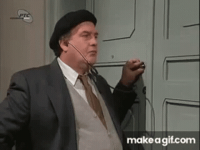 A Man In A Suit And Beret Is Standing In Front Of A Door . GIF