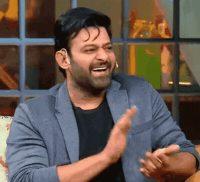 A Man In A Suit And Black Shirt Is Clapping His Hands And Smiling . GIF
