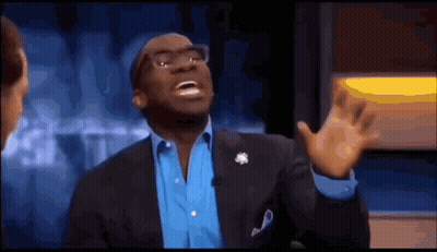 A Man In A Suit And Blue Shirt Is Making A Funny Face While Talking On A Television Show . GIF