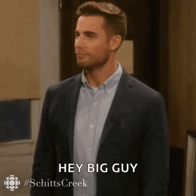 A Man In A Suit And Blue Shirt Is Saying Hey Big Guy . GIF