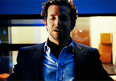 A Man In A Suit And Blue Shirt Is Standing In A Room GIF