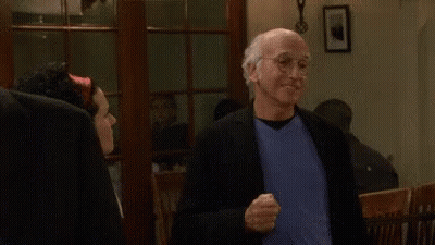 A Man In A Suit And Blue Shirt Is Standing Next To A Woman In A Room And Smiling . GIF