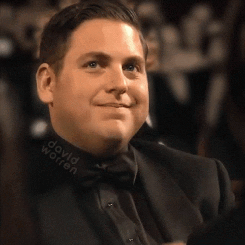 A Man In A Suit And Bow Tie Has David Worren Written On His Collar GIF