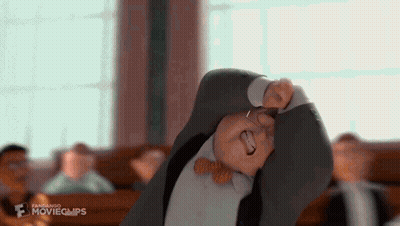 A Man In A Suit And Bow Tie Is Making A Funny Face In A Classroom . GIF